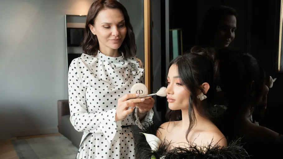 Woman applying makeup to another woman indoors.