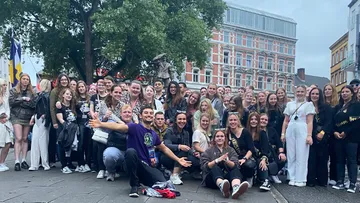 Large group posing outdoors in urban setting.