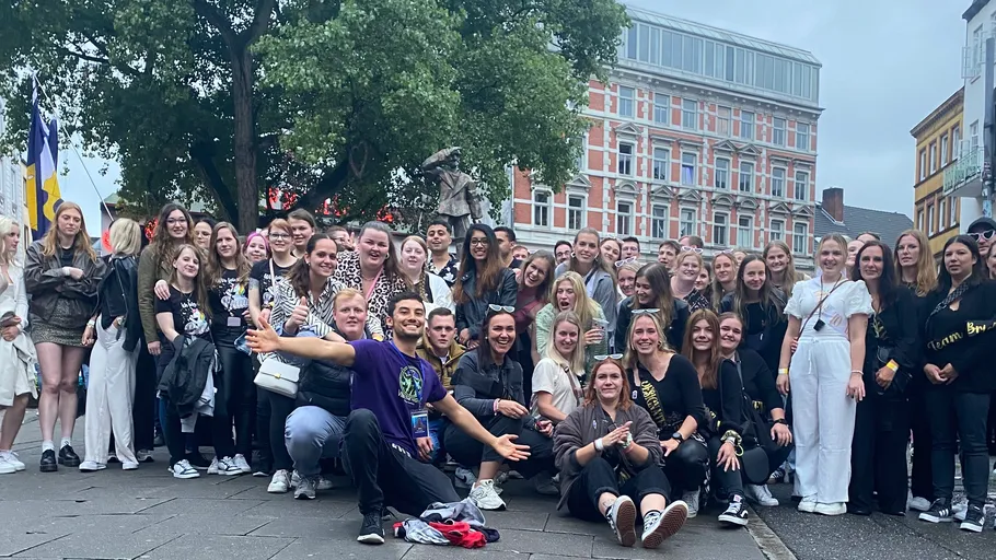 Large group posing outdoors in urban setting.