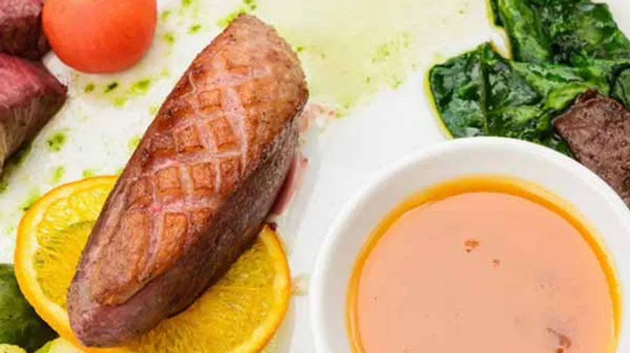 Gekochte Entenbrust mit Sauce und Grünzeug.
