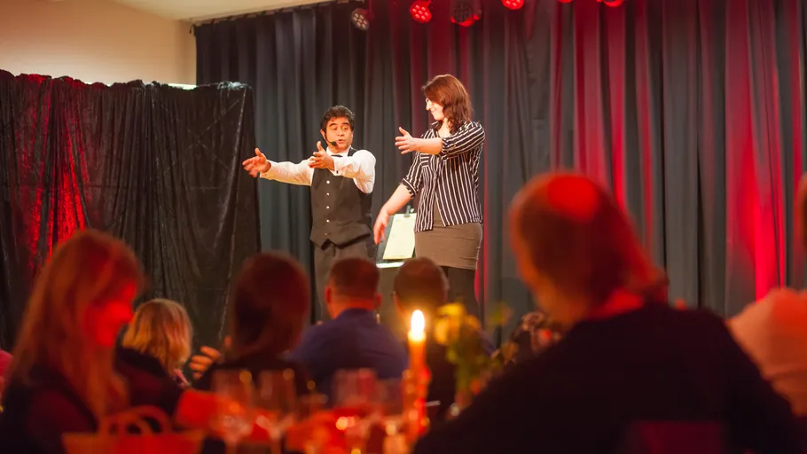 Magician performing on stage with audience watching.