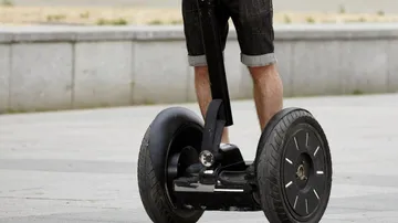 Person fährt Segway auf gepflastertem Weg.