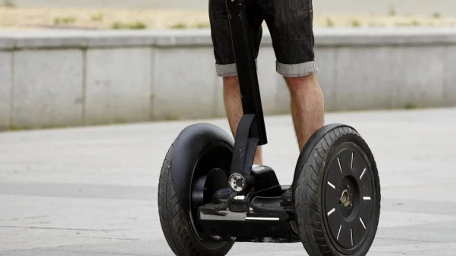 Person fährt Segway auf gepflastertem Weg.