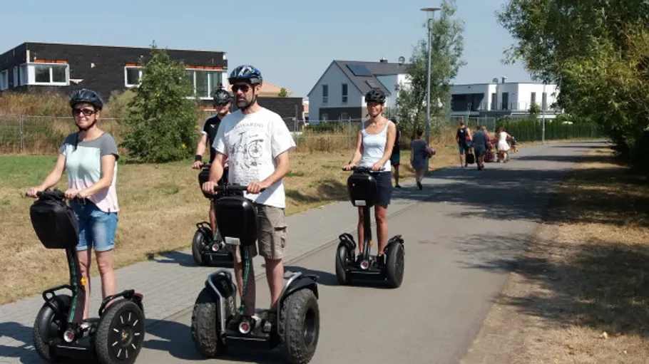 Personen fahren Segways auf einem gepflasterten Weg.