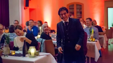 Smiling performer with microphone among dining guests.