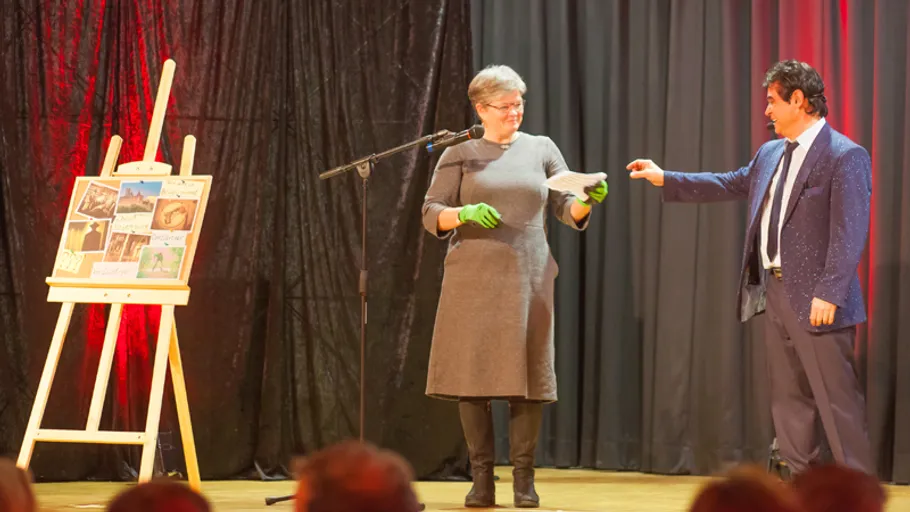 Two people on stage with an easel.