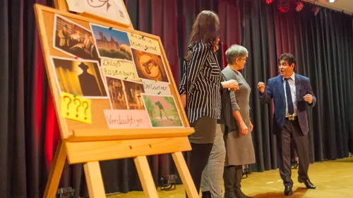 Drei Personen diskutieren eine Tafel mit Fotos.