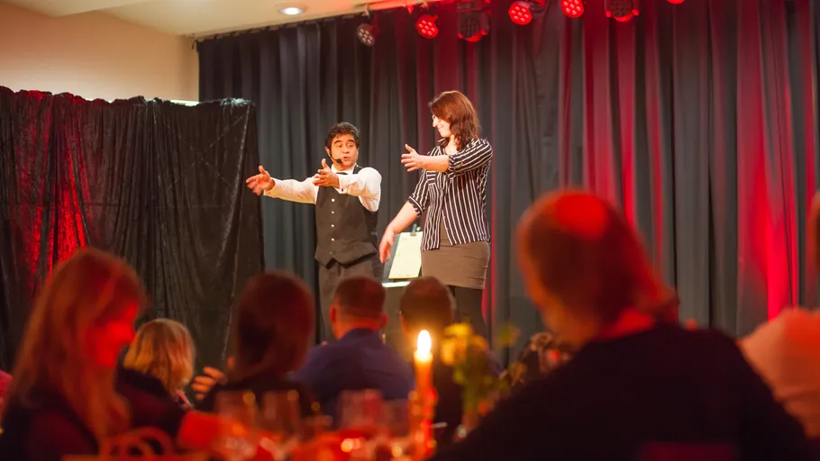 Magician performing on stage with an assistant.