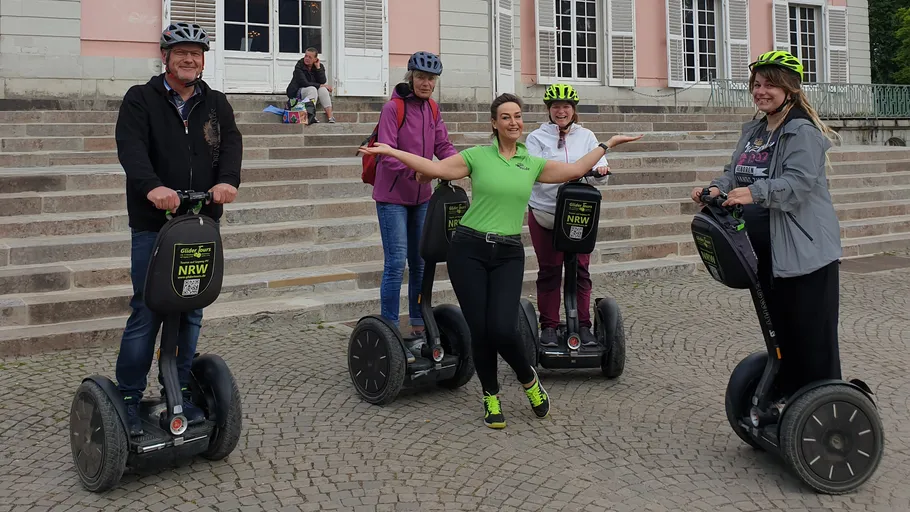 Gruppe auf Segways posiert vor Treppen.
