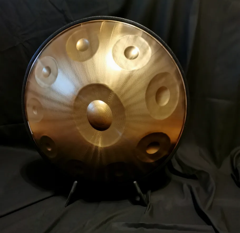 Metall-Handpan auf schwarzem, drapiertem Hintergrund.