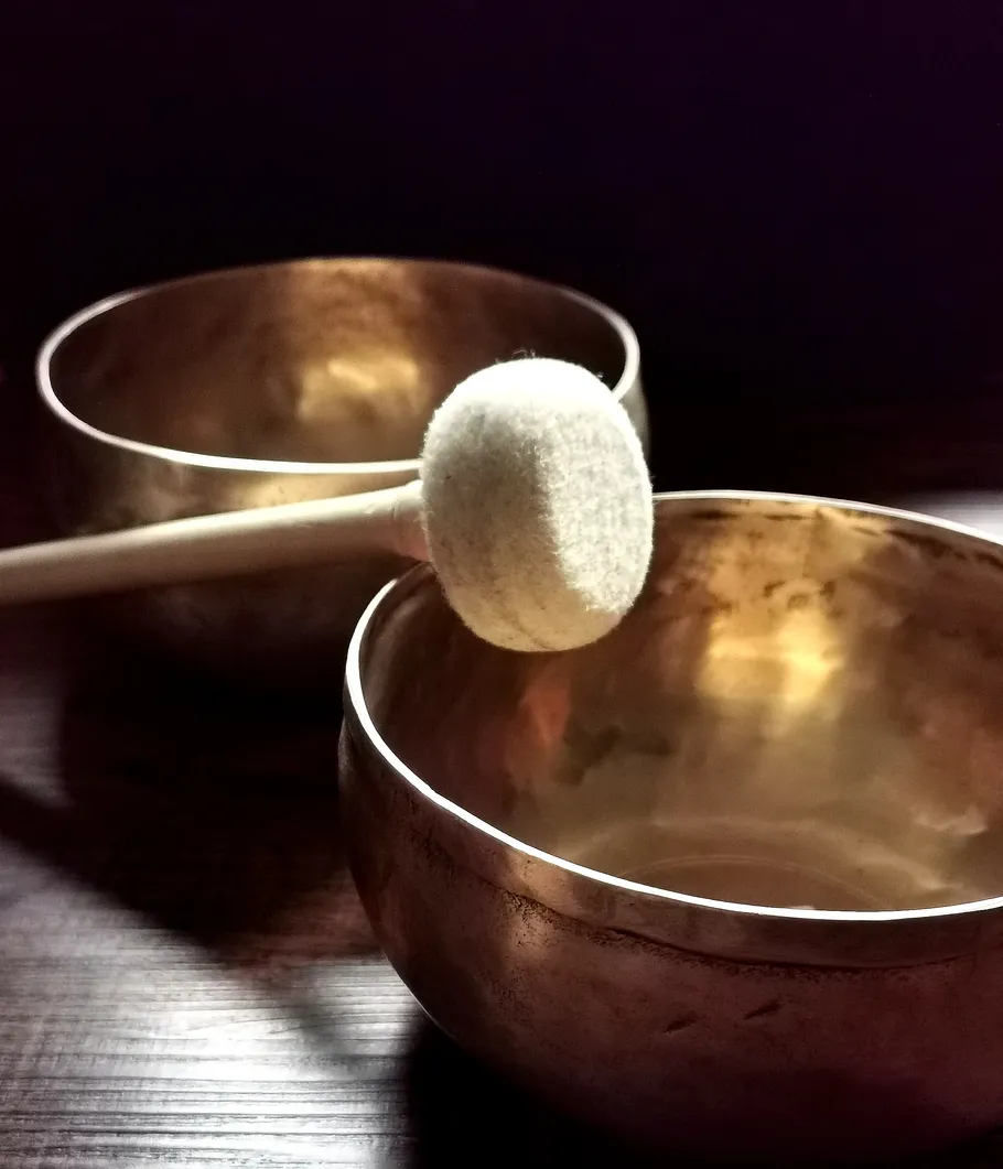 Singing bowls and mallet on a table.