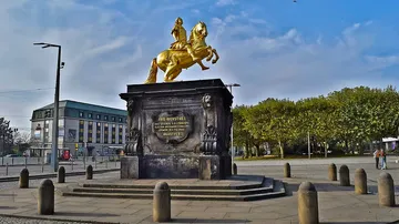 Goldene Reiterstatue auf Sockel im Freien.