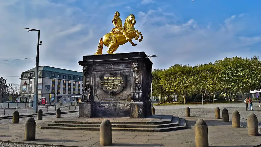 Golden equestrian statue on pedestal outdoors.