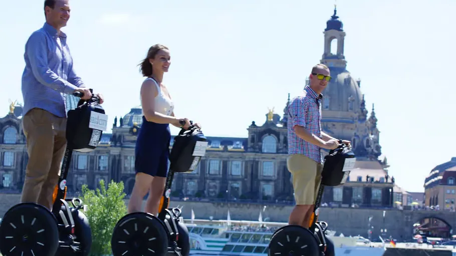Three people riding Segways near historic building.