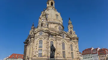 Barockkirche mit Statue, unter blauem Himmel.