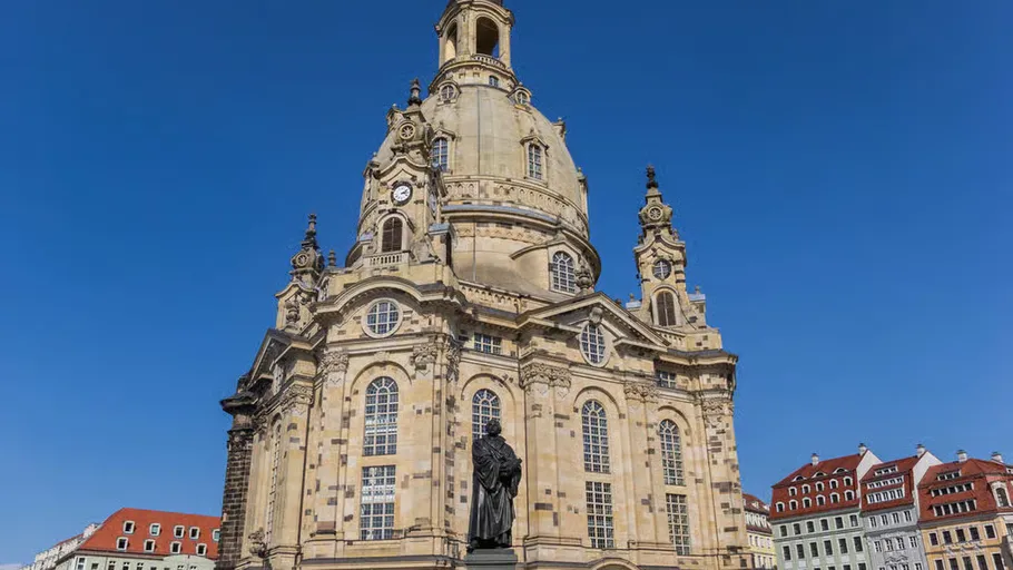 Barockkirche mit Statue, unter blauem Himmel.