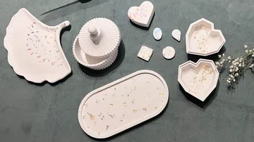 Dekorative Tabletts und Behälter auf grauer Fläche.
