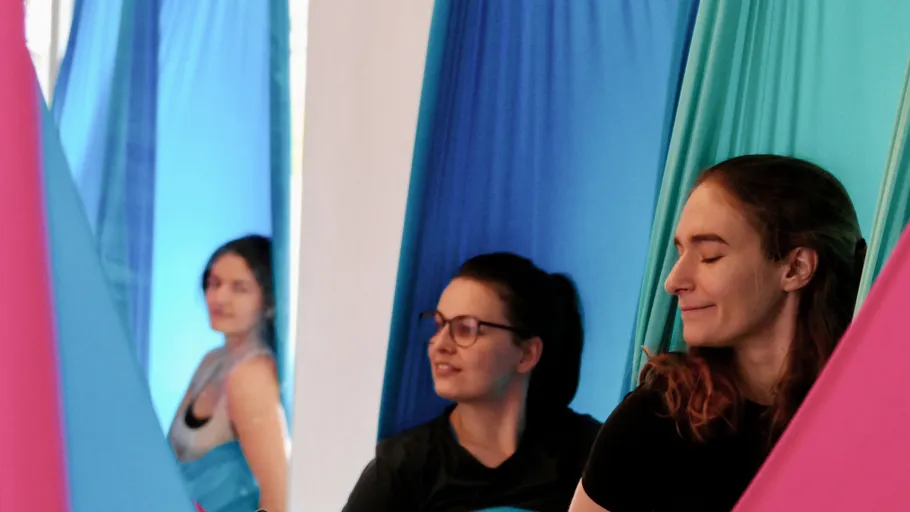 Drei Frauen machen Aerial-Yoga drinnen.