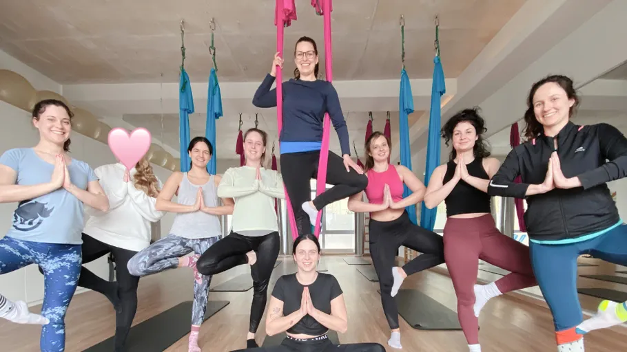 Group doing aerial yoga poses in studio.