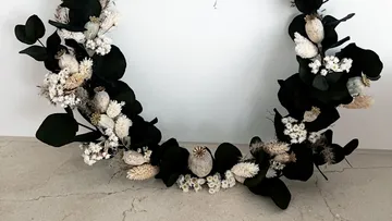 Kranz mit weißen Blumen auf Tisch.