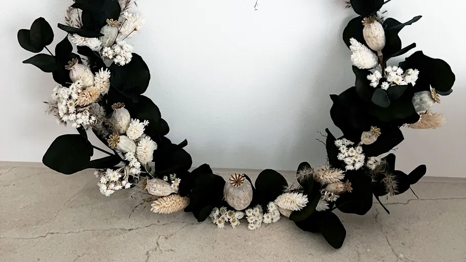 Kranz mit weißen Blumen auf Tisch.