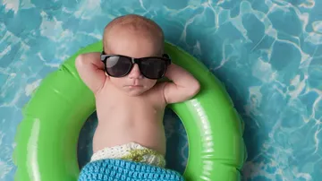 Baby mit Sonnenbrille entspannt auf Schwimmring.