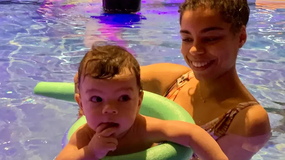 Baby in pool with woman, using float.