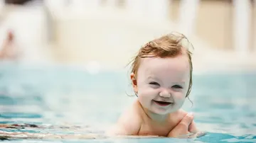 Baby lächelt beim Schwimmen im Pool.