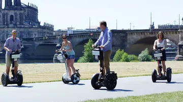 Vier Personen fahren Segways nahe einem historischen Gebäude.