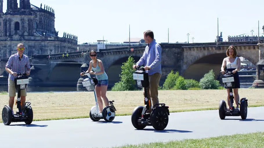 Four people ride segways near a historic building.