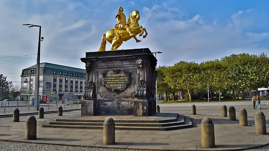 Goldene Pferdestatue auf städtischem Platz.