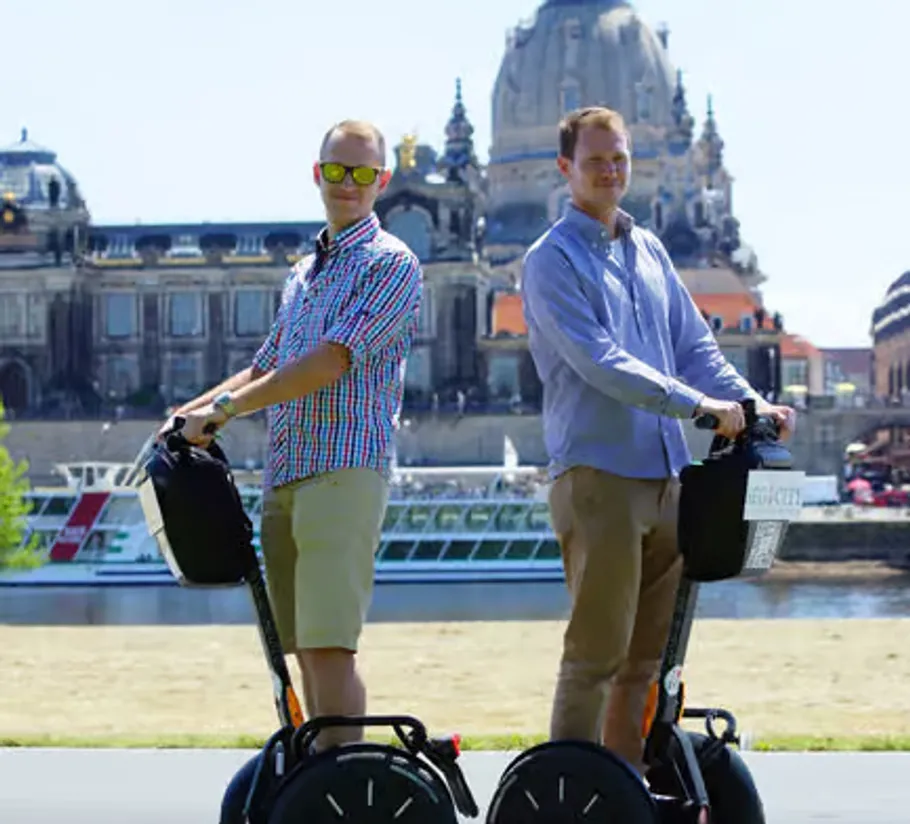Zwei Personen auf Segways in städtischer Umgebung.