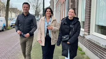 Three people walking on a city sidewalk.