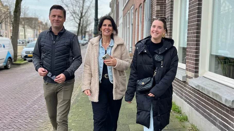 Three people walking on a city sidewalk.