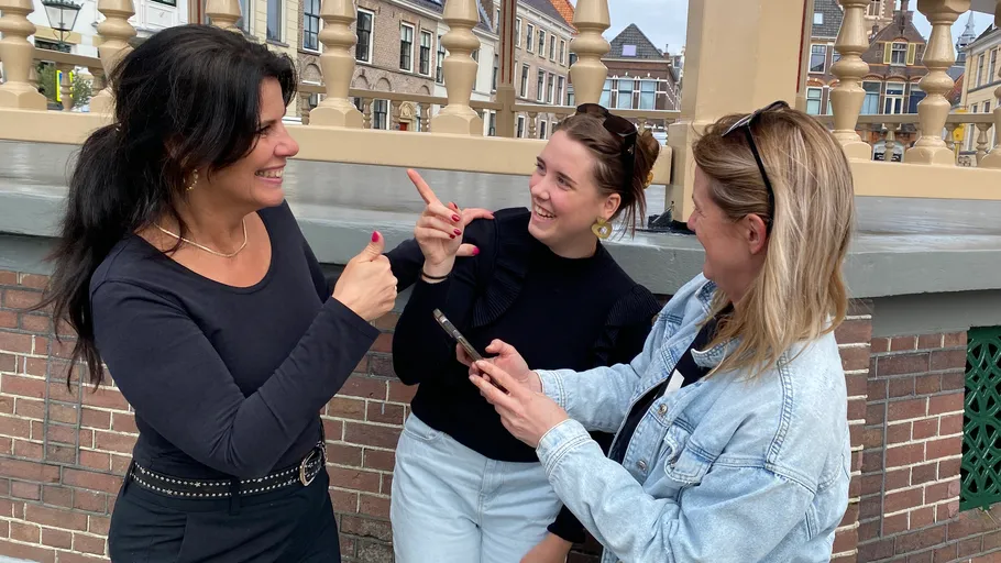 Three women happily talking outside on a street.