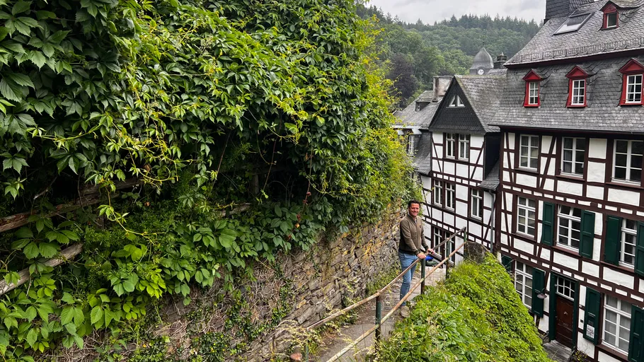 Man standing on path between greenery and buildings.