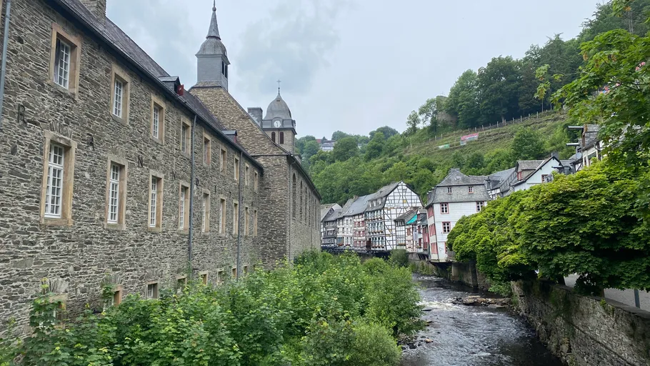 Historic buildings by a flowing river in a forested area.