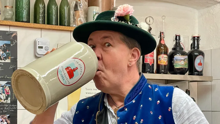Mann trinkt aus einem großen Bierkrug drinnen.
