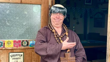 Man dressed as monk at wooden doorway.