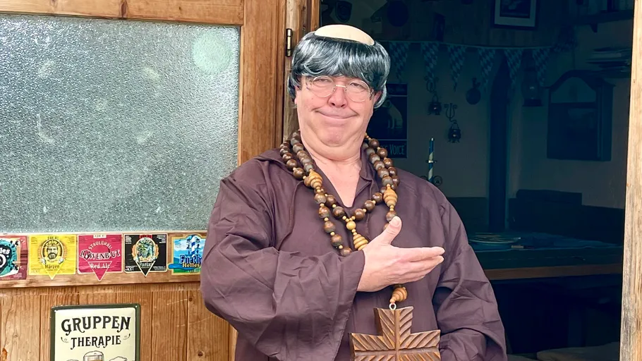 Mann als Mönch verkleidet an Holztür.