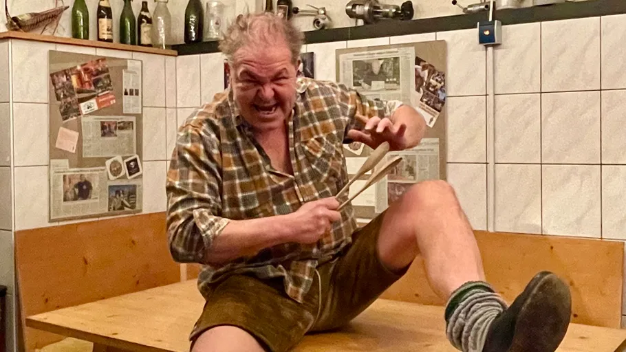 Mann im Karohemd spielt Löffel auf einem Tisch.