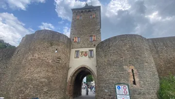 Stone gate tower with arched entrance, cloudy sky.