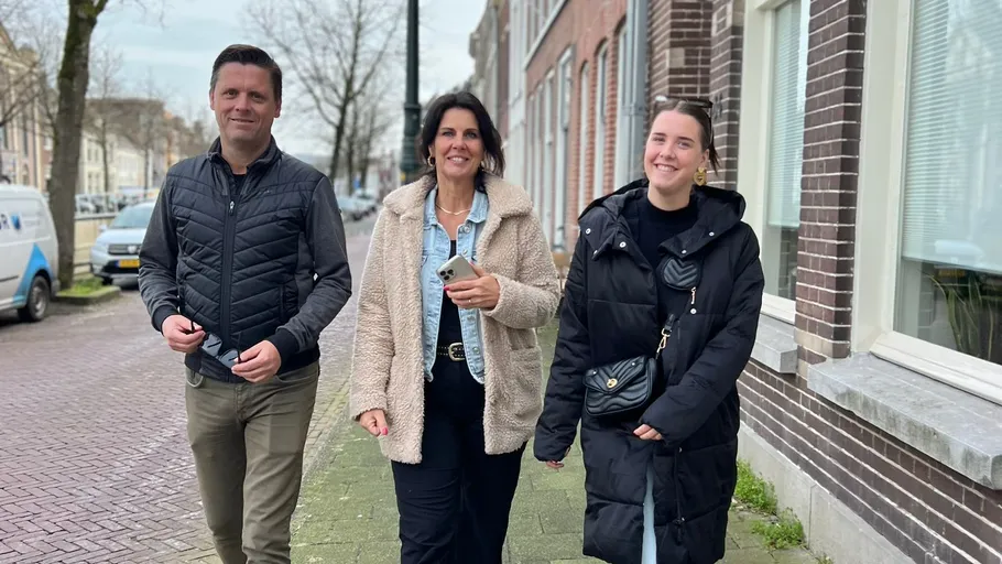 Three people walking on a city sidewalk.