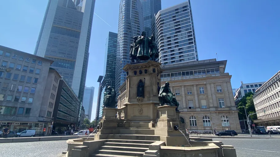 Statue mit Wolkenkratzern im Stadtbild.
