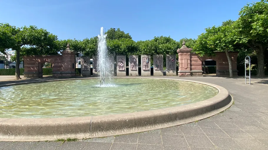 Brunnen sprüht Wasser im sonnigen Park.