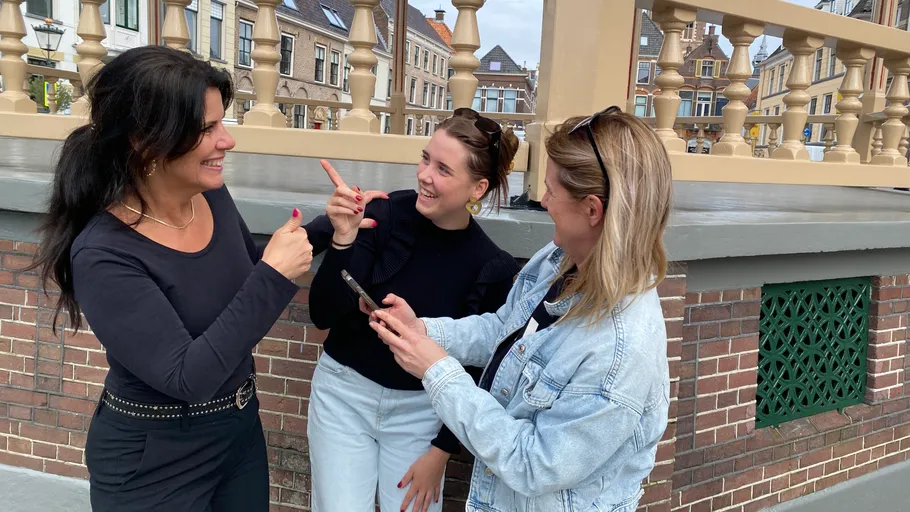 Three women talking, leaning on a railing.