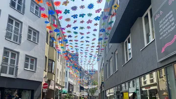 Colorful flower decorations hanging above city street.