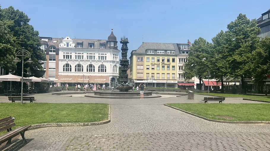 Menschen laufen in der Stadt am Brunnen.