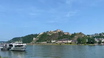 Boat docked on river with hill fortress.