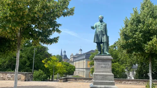 Statue eines Mannes im Park mit Gebäuden.